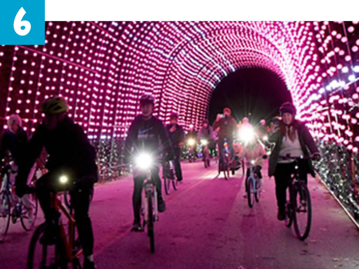 Cyclists riding under tunnel covered in red lights